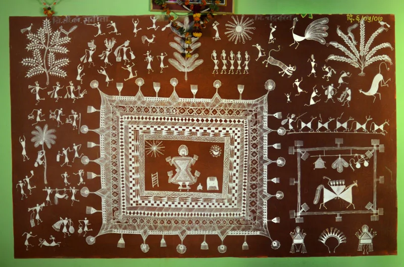 A traditional Warli painting done in white over a red ochre background. Panchasiriya is in the dev chauk in the bottom right of the picture. there is a lagna chauk in the centre.